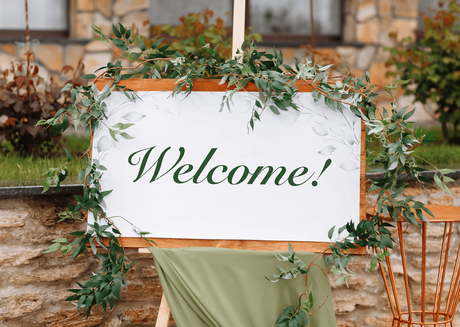 Decorative welcome sign with greenery on easel